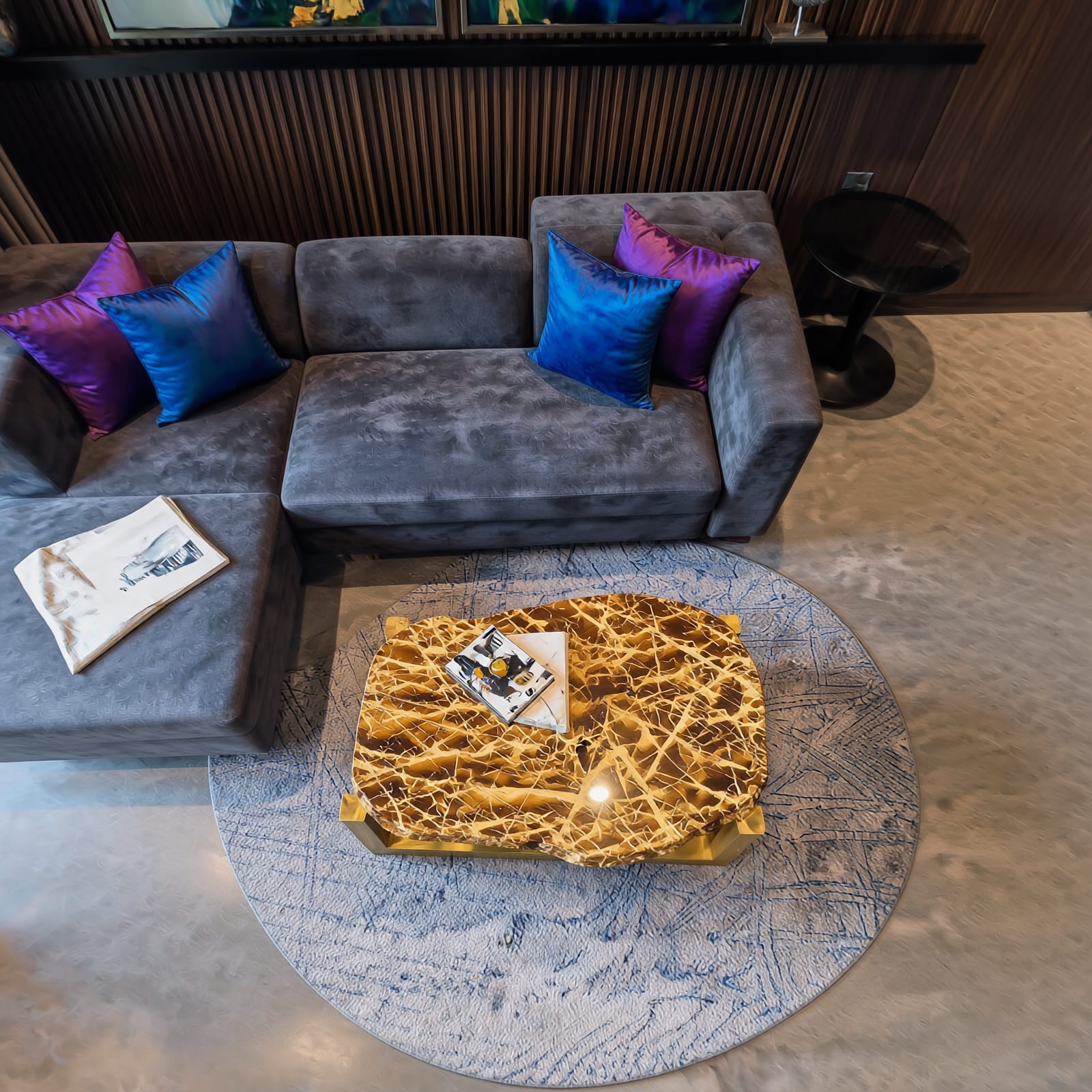 A Moody, Jewel-Toned Living Room in Kolkata: Design Breakdown by Estate Lookup Interiors 4 Top view of luxury living room by interior designer in Kolkata with grey velvet sectional sofa, jewel-tone cushions and stone-top brass coffee table